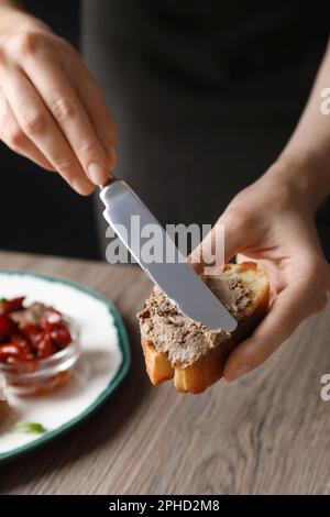 Femme qui répandait un délicieux pâté sur du pain sur une table, en gros plan Banque D'Images