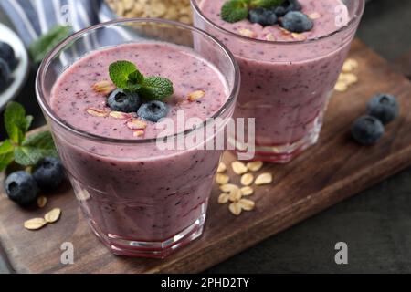 Verres de délicieux smoothie aux myrtilles avec flocons d'avoine sur bois Banque D'Images