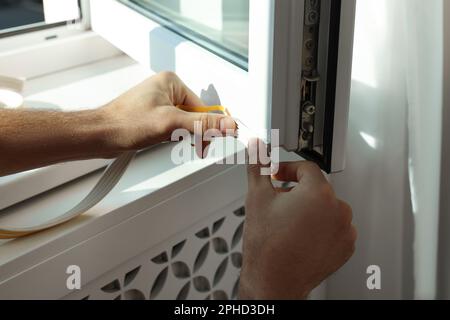 Homme mettant la bande de traction en caoutchouc sur la fenêtre, gros plan Banque D'Images