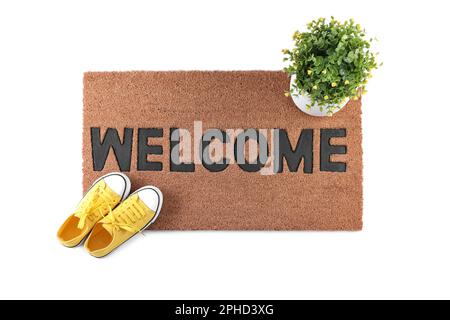 Tapis de porte élégant avec mot Welcome, maison et chaussures sur fond blanc, vue de dessus Banque D'Images