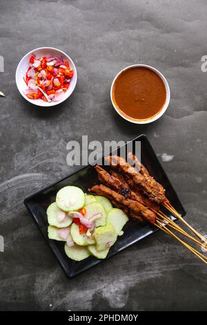 satay de poulet ou satay de poulet servi avec du lontong, du gâteau de riz et de la sauce aux arachides. Banque D'Images