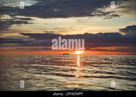 Coucher de soleil pittoresque sur la plage de Siquijor aux Philippines, tout le ciel nuageux brille de couleur rouge feu et orange doré. Banque D'Images