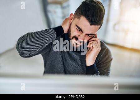 HES a de nouveau fait des choses au travail... un jeune designer qui a l'air stressé tout en parlant sur un téléphone portable dans un bureau. Banque D'Images