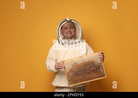 Apiculteur en forme de ruche de maintien uniforme avec nid d'abeille sur fond jaune Banque D'Images