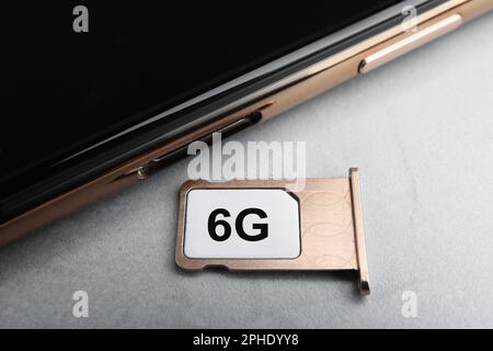 Concept Internet. 6G carte SIM dans le plateau et smartphone sur une table gris clair, gros plan Banque D'Images