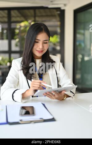 Femme d'affaires ou chef d'entreprise asiatique du millénaire attirante et professionnelle utilisant sa tablette numérique à son bureau. Banque D'Images