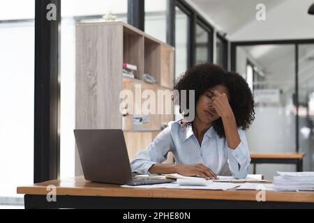 L'employé de comptable ouvrier s'est ennuyé de maux de tête et de stress. Femme noire surtravaille au bureau Banque D'Images