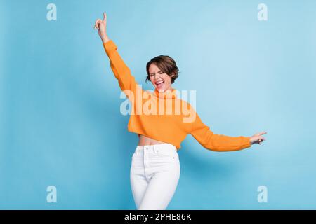 Photo portrait de jolie jeune fille danse concert partie ont plaisir excité porter vêtement orange tendance isolé sur fond bleu de couleur Banque D'Images