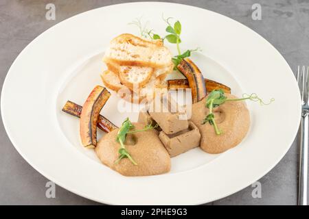 Foie gras de canard à la sauce et pain croustillant sur une assiette en porcelaine blanche Banque D'Images