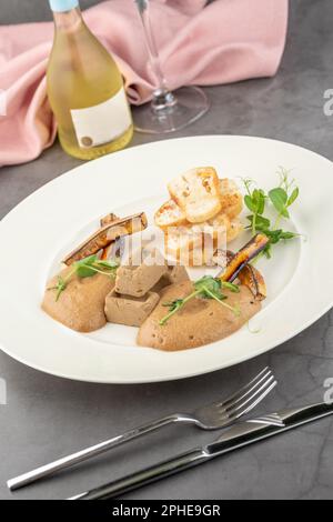 Foie gras de canard à la sauce et pain croustillant sur une assiette en porcelaine blanche Banque D'Images