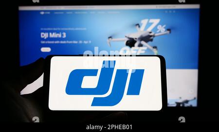 Personne tenant un smartphone avec le logo de la compagnie de drone SZ DJI Technology Co. Ltd. Sur l'écran devant le site Web. Mise au point sur l'affichage du téléphone. Banque D'Images