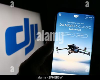 Personne tenant le téléphone portable avec le site Web de la compagnie de drone SZ DJI Technology Co. Ltd. À l'écran devant le logo. Concentrez-vous sur le centre de l'écran du téléphone. Banque D'Images