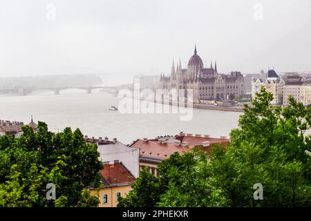 Vue brumeuse activée Fantastique Parlement hongrois à Budapest et petits bateaux dans l'eau du Danube ! Circulation de voitures à côté du célèbre bâtiment Banque D'Images