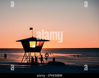 Cette image présente une tour de maître-nageur située sur la plage au coucher du soleil, avec un ciel spectaculaire d'oranges et de roses Banque D'Images