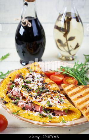 Omelette frite farcie à la saucisse, aux tomates, aux légumes verts et au fromage. Délicieux petit déjeuner facile Banque D'Images