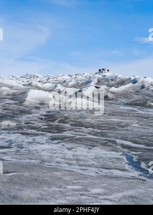 Les touristes rangeant sur la glace. Les sédiments bruns sur la glace sont créés par la fonte rapide de la glace. Paysage de la calotte glaciaire du Groenland près de Kanger Banque D'Images