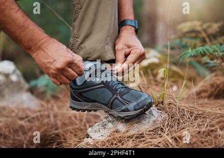 Gros plan, mains et chaussures de sport sur la randonnée, commencez la marche et le fitness pour le bien-être, l'entraînement et l'exercice. Homme, randonneur et gars attachant la chaussure, préparez-vous pour Banque D'Images