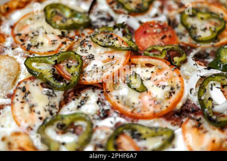 Une vue de dessus d'une pizza fraîchement cuite, avec une délicieuse garniture de fromage fondu et de tomates fraîchement coupées Banque D'Images