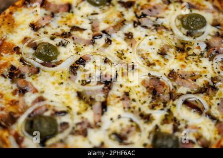 Une délicieuse pizza est présentée sur une table, recouverte d'un assortiment de légumes, viandes et fromages Banque D'Images