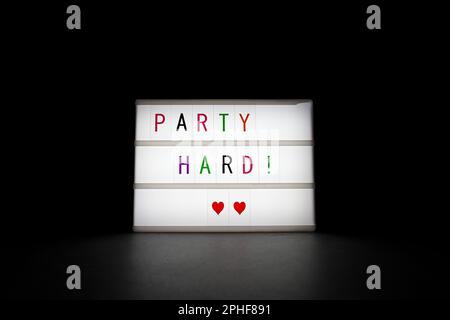 Le néon lumineux ''Party Time' est dans l'obscurité sur fond noir Banque D'Images