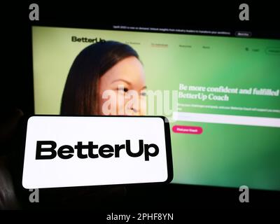 Personne tenant un smartphone avec le logo de la société de coaching américaine BetterUp à l'écran devant le site Web. Mise au point sur l'affichage du téléphone. Banque D'Images