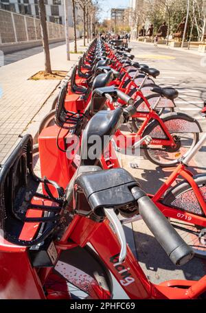 Les vélos électriques du service Bgivrage de Barcelone garés dans un seul fichier et en chargeant leurs batteries dans un parking linéaire. Banque D'Images