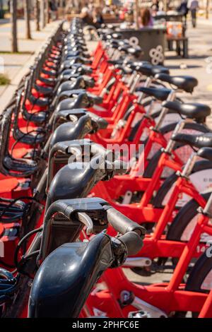 Les vélos électriques du service Bgivrage de Barcelone garés dans un seul fichier et en chargeant leurs batteries dans un parking linéaire. Banque D'Images