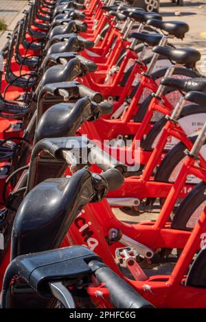 Les vélos électriques du service Bgivrage de Barcelone garés dans un seul fichier et en chargeant leurs batteries dans un parking linéaire. Banque D'Images