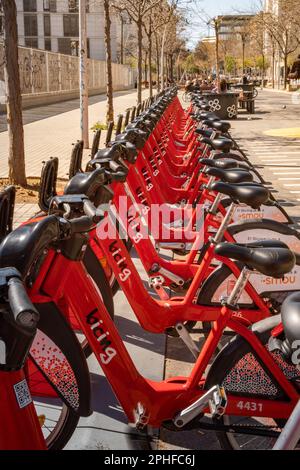 Les vélos électriques du service Bgivrage de Barcelone garés dans un seul fichier et en chargeant leurs batteries dans un parking linéaire. Banque D'Images