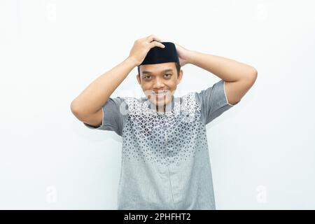 Indonésien asiatique musulman souriant porte un chapeau noir appelé peci ou songkok Banque D'Images