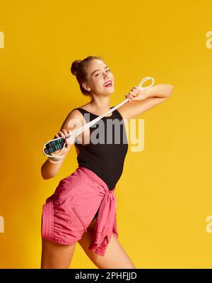 Portrait d'une jeune fille souriante faisant de l'exercice avec corde à sauter sur fond jaune Banque D'Images