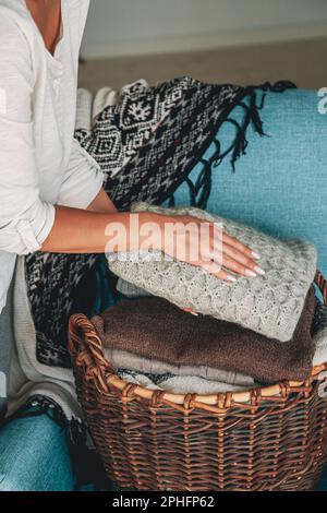 Les mains des femmes plient une pile de chandails tricotés chauds en osier b. Banque D'Images