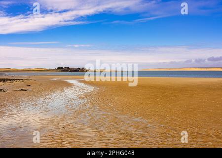 Vue sur le sable jusqu'au fort Belan avec la plage de Newborough sur Anglesey en traversant le détroit de Menai. Dinas Dinlle, Caernarfon, Gwynedd, nord du pays de Galles, Royaume-Uni, Grande-Bretagne Banque D'Images