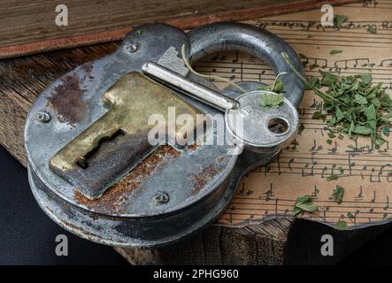 Bangkok,Thai - 17 mars 2023 : la clé et le cadenas en fer Vintage avec feuilles de cannabis hachées sur l'ancienne note de musique vintage avec l'ancien plan en bois Banque D'Images