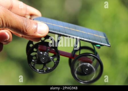 Voiture de modèle de travail à énergie solaire tenue à la main avec 3D roues imprimées et un fond naturel Banque D'Images