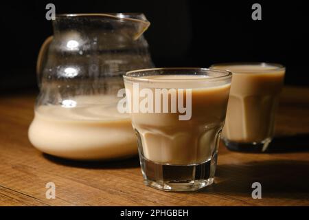 Café avec lait dans la cafetière et deux tasses à espresso fines sur fond de bois Banque D'Images