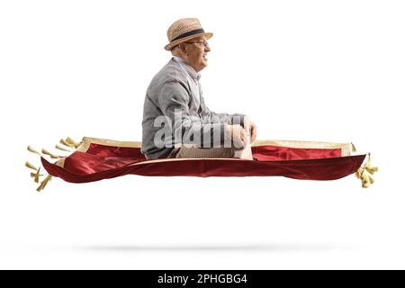 Photo de profil d'un homme âgé volant avec un tapis de velours rouge isolé sur fond blanc Banque D'Images