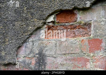 Mur de briques rendu avec un ciment dur qui craque et tombe Banque D'Images