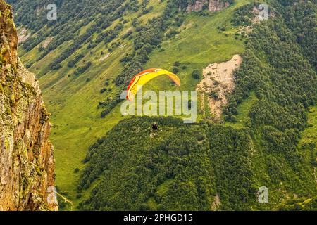 Parachute en tandem avec parachute - parapentes en Géorgie volant près d'une énorme falaise au-dessus des arbres dans la vallée très en dessous Banque D'Images