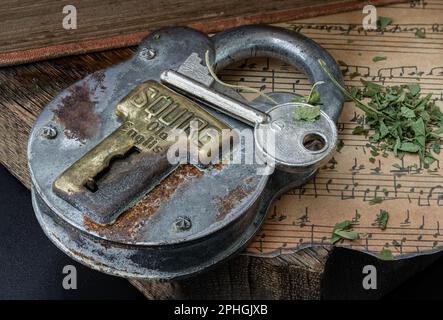 Bangkok,Thai - 17 mars 2023 : la clé et le cadenas en fer Vintage avec feuilles de cannabis hachées sur l'ancienne note de musique vintage avec l'ancien plan en bois Banque D'Images