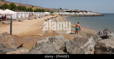 Odessa, Ukraine -2022: Barrières militaires métalliques, hérissons anti-chars sur la plage de la ville maritime. Les vacanciers prennent le soleil à côté des hérissons anti-tank de fer. Clôtures f Banque D'Images