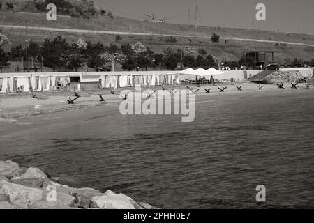 Odessa, Ukraine -2022: Barrières militaires métalliques, hérissons anti-chars sur la plage de la ville maritime. Les vacanciers prennent le soleil à côté des hérissons anti-tank de fer. Clôtures f Banque D'Images