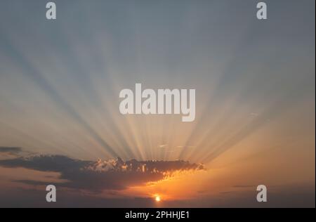 Des faisceaux de lumière éblouissants qui traversent les nuages au coucher du soleil, la lueur du soleil sur les nuages avec un temps parfait à la fin d'une journée d'été Banque D'Images