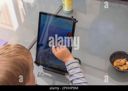 Gros plan sur un enfant mignon jouant sur une tablette. Suède. Banque D'Images