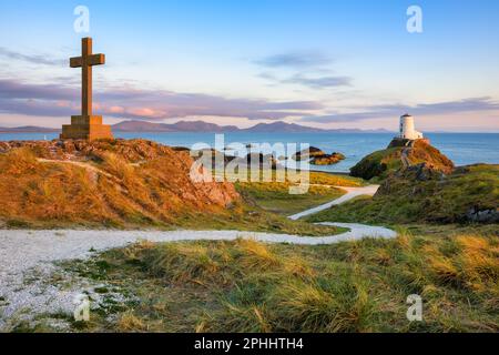 Le phare TWR Mawr et la croix de St Dwynwen, les monuments emblématiques de l'île d'Anglesey, vue panoramique sur le coucher du soleil, la côte du pays de Galles, Royaume-Uni Banque D'Images