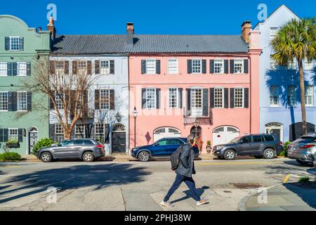 Les piétons traversent la rue en face de Rainbow Row, un ensemble de maisons historiques, à Charleston, Caroline du Sud, États-Unis. Banque D'Images