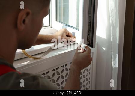 Homme mettant la bande de traction en caoutchouc sur la fenêtre, gros plan Banque D'Images