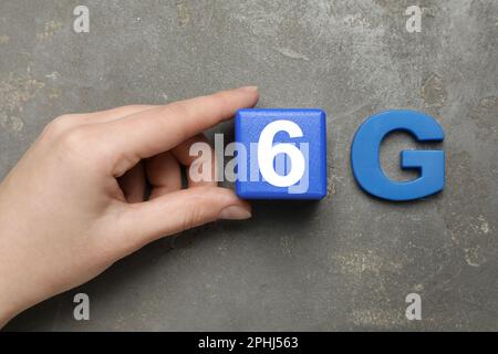 Concept Internet. Femme portant un cube en bois bleu et une lettre sur une table grise, vue de dessus Banque D'Images