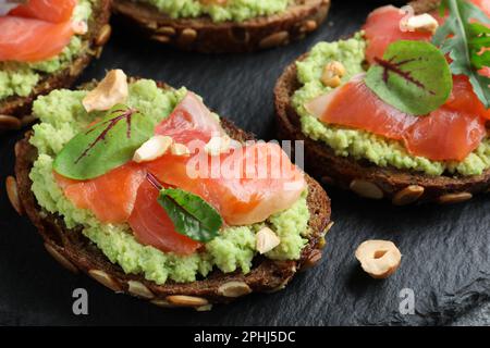 Délicieux sandwichs au saumon, à l'avocat et aux herbes sur plaque d'ardoise, en gros plan Banque D'Images