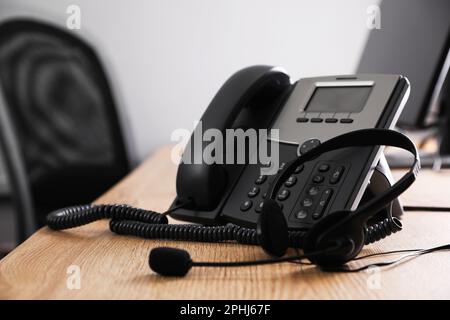 Téléphone fixe et casque sur un bureau en bois. Service d'assistance téléphonique Banque D'Images